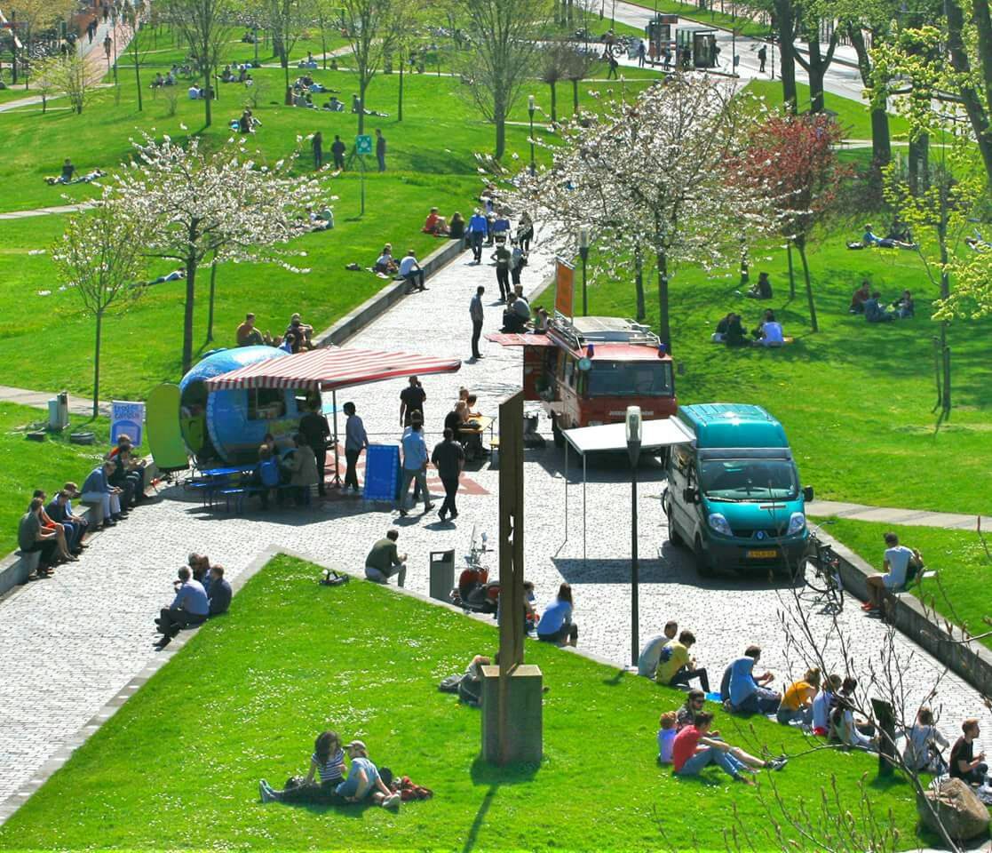 De foodtruck tussen de bloesem op de campus van de TU Delft, met mensen in het gras